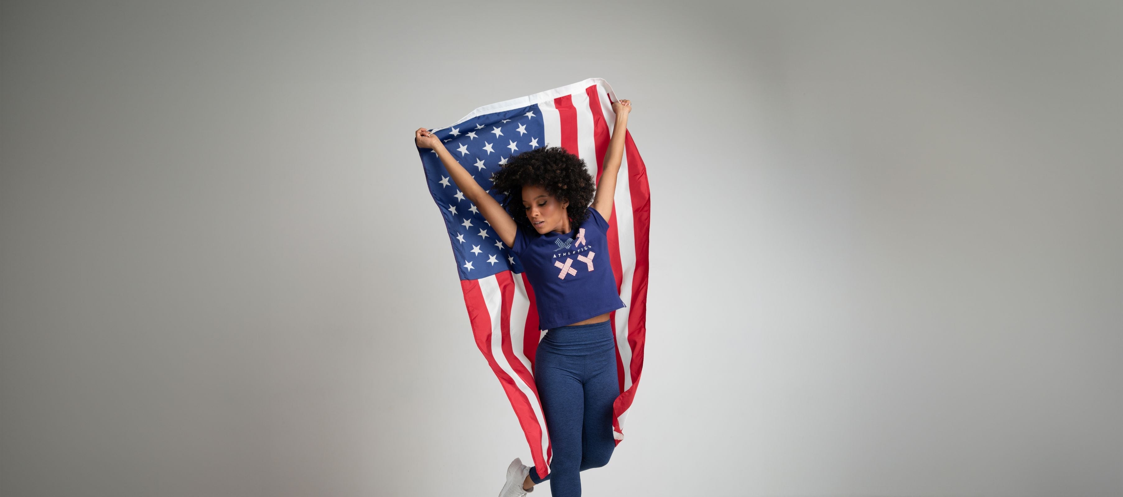 Two athletes posing with an American flag and wearing the XX-XY Roar Tee in red. 